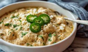 Bowl of crockpot creamy white chicken chili topped with avocado sour cream and tortilla strips