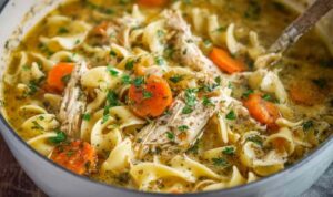 Easy Chicken Noodle Soup Bowl Bowl of easy chicken noodle soup with egg noodles, carrots, celery, and fresh herbs