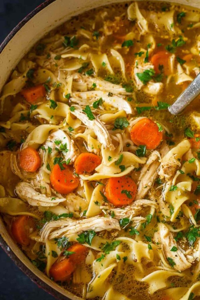 Bowl of easy chicken noodle soup with egg noodles, carrots, celery, and fresh herbs
