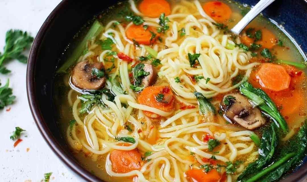 Quick chicken ramen in white bowl topped with soft boiled eggs green onions and sesame seeds