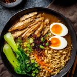 Bowl of vegan vegetable noodle soup with angel hair noodles and fresh parsley garnish