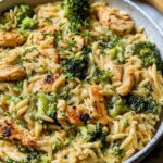 Cheesy chicken broccoli orzo in a large skillet with melted cheddar cheese and tender broccoli florets