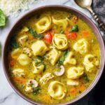 Chicken pesto tortellini soup in bowl with fresh basil and parmesan cheese