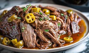 Shredded crockpot Mississippi pot roast in slow cooker with pepperoncini and rich gravy