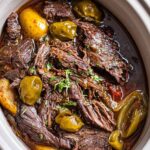 Shredded crockpot Mississippi pot roast in slow cooker with pepperoncini and rich gravy