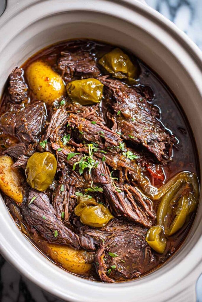 Shredded crockpot Mississippi pot roast in slow cooker with pepperoncini and rich gravy