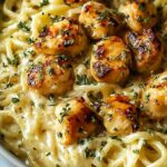 Garlic butter chicken bites with creamy Parmesan pasta in skillet topped with fresh parsley