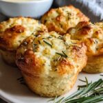 Golden brown garlic rosemary focaccia muffins on cooling rack with fresh rosemary sprigs