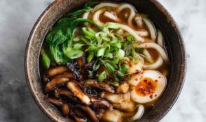 Miso udon noodle soup in bowl with teriyaki mushrooms and green onions
