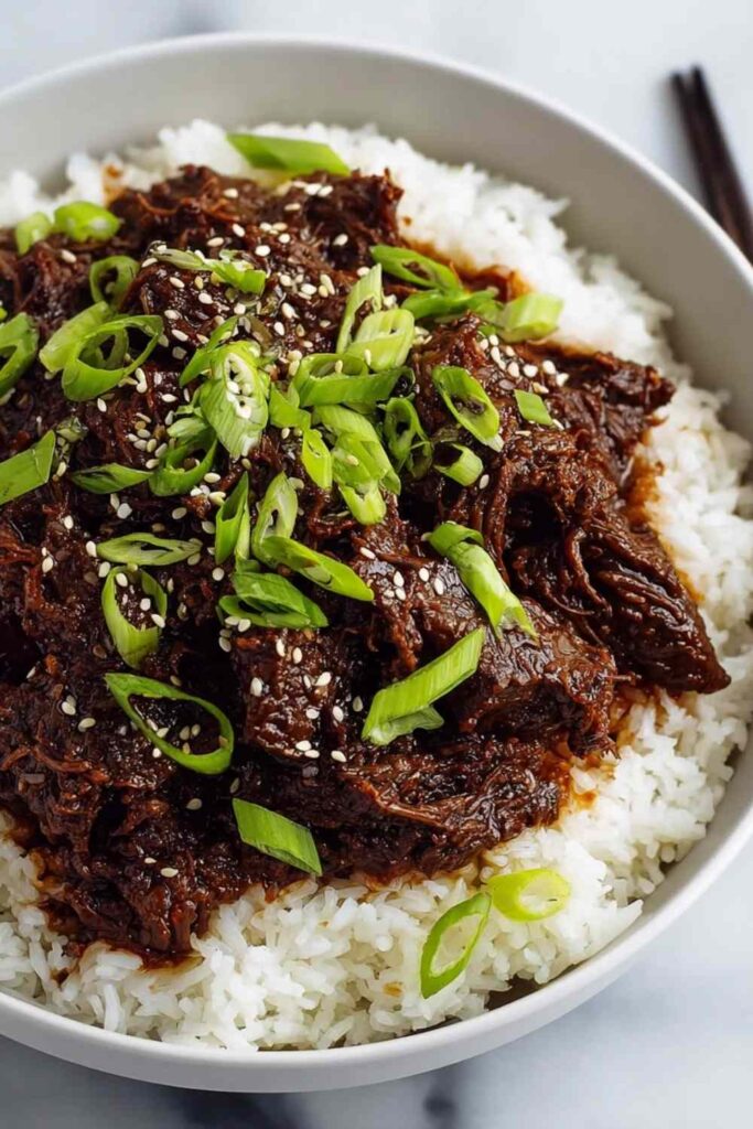 Slow Cooker Korean Beef served over white rice with green onions