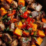 Colorful plate of steak bites with sweet potatoes and peppers garnished with fresh parsley