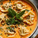Thai curry dumpling soup in white bowl with coconut milk broth and fresh herbs