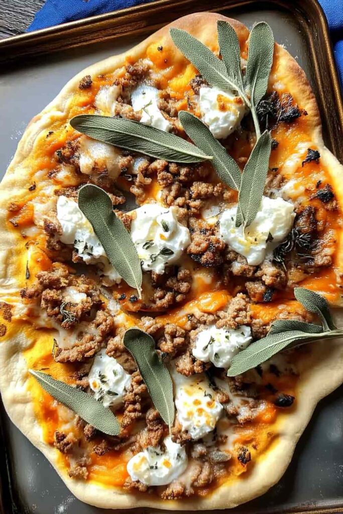 Autumn naan pizzas topped with sausage, caramelized shallots, and melted fontina cheese on baking sheet
