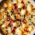 Bacon Cheddar Gnocchi Soup in white bowl with crispy bacon pieces and melted cheddar