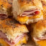 Baked ham and cheese sliders on King's Hawaiian rolls with golden poppy seed butter topping in baking dish