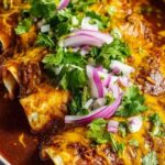 Birria enchiladas topped with melted cheese and cilantro served with consommé