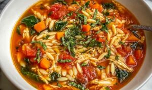 Chicken Orzo Tomato Soup Bowl of Chicken Orzo Tomato Soup garnished with fresh basil and served with crusty bread