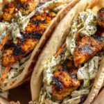 Chicken pitas with herby ranch slaw on white plate with fresh vegetables