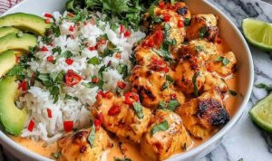 Coconut chicken rice bowl with tender chicken pieces, jasmine rice, shredded carrots, cucumber, and cilantro garnish