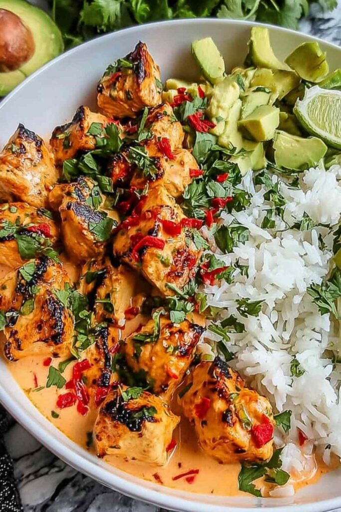 Coconut chicken rice bowl with tender chicken pieces, jasmine rice, shredded carrots, cucumber, and cilantro garnish