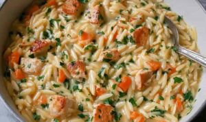 Creamy chicken pot pie orzo in white bowl with vegetables and tender chicken pieces