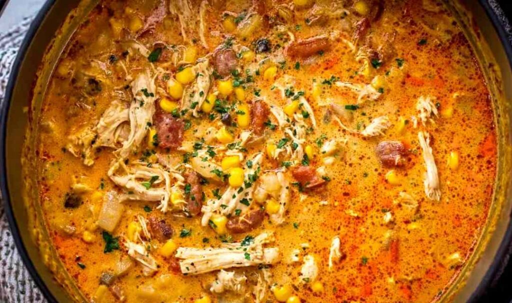 Bowl of creamy chipotle chicken soup topped with avocado cilantro and tortilla strips