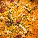 Bowl of creamy chipotle chicken soup topped with avocado cilantro and tortilla strips