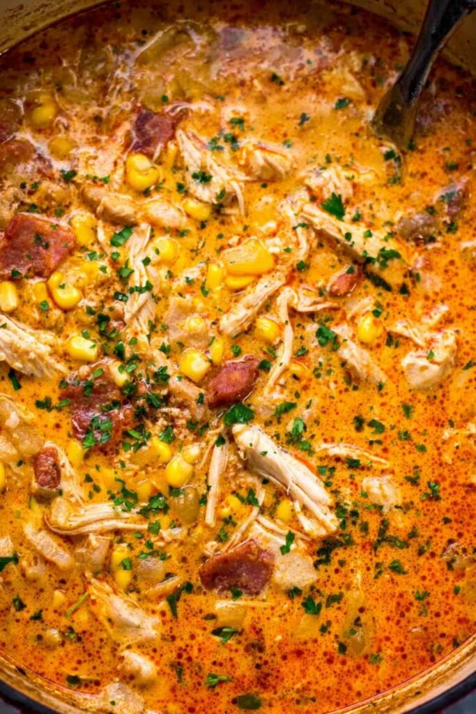 Bowl of creamy chipotle chicken soup topped with avocado cilantro and tortilla strips