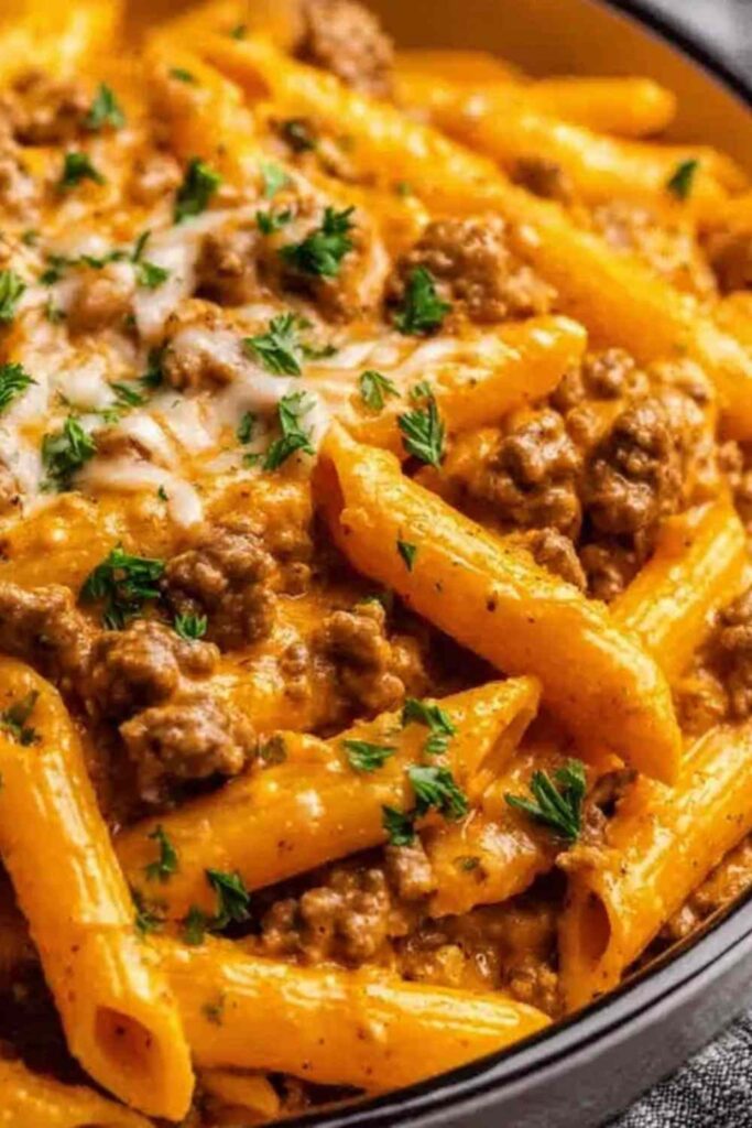 Creamy high protein beef pasta in a large skillet with melted cheese and fresh parsley