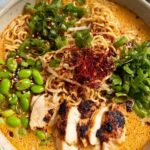 Creamy marry me chicken ramen in a bowl with sliced chicken, noodles, and garnishes
