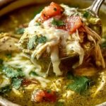 Crock-pot green enchilada chicken soup in white bowl topped with avocado cheese and cilantro
