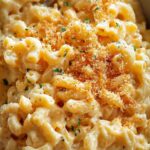 Crockpot mac and cheese in white slow cooker with wooden spoon showing creamy cheese sauce