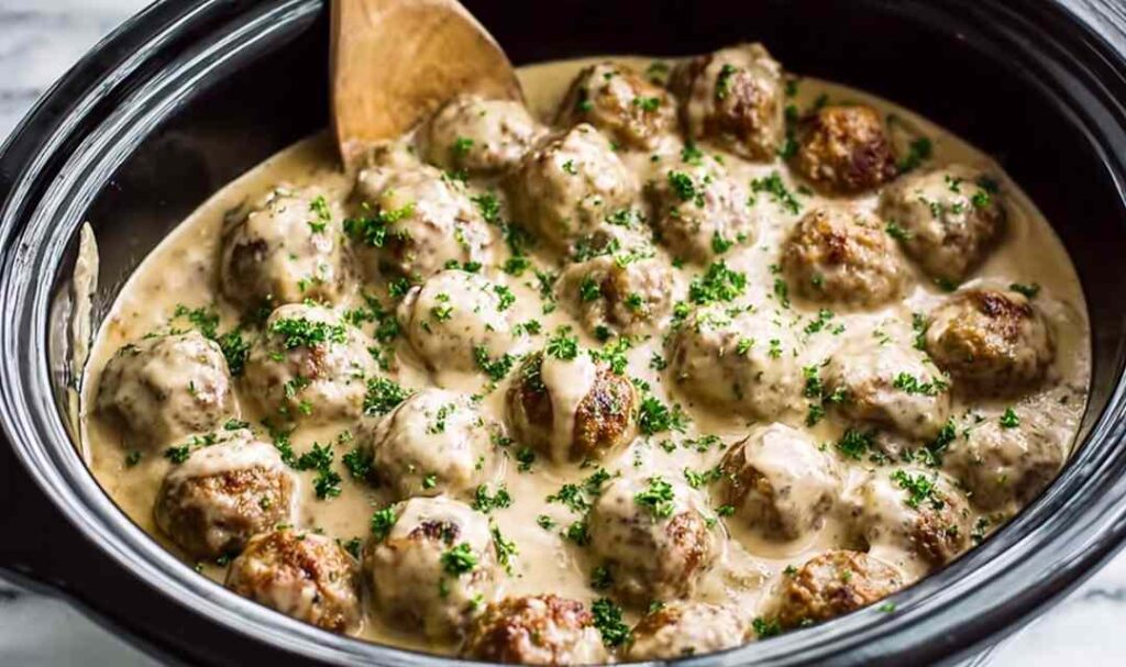 Crockpot Swedish meatballs in creamy gravy served over egg noodles with parsley garnish