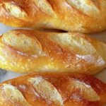 Crusty mini baguettes with golden brown crust on cooling rack