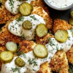 Golden crispy dill pickle parmesan chicken on white plate with fresh dill garnish