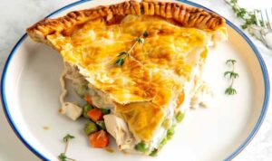 Easy chicken pot pie with golden flaky crust and creamy chicken filling on white plate