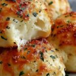 Garlic butter cheese bombs on baking sheet with melted mozzarella cheese inside