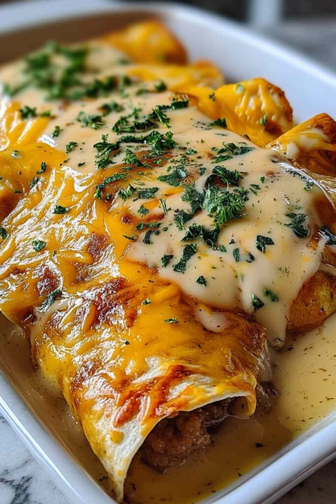 Southern breakfast enchiladas with sausage gravy on white plate with fresh herbs garnish