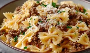 Garlic butter bowtie pasta with beef served in white bowl with parmesan and parsley garnish