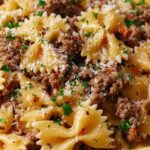 Garlic butter bowtie pasta with beef served in white bowl with parmesan and parsley garnish