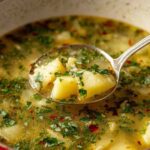 Creamy garlic potato soup in white bowl with fresh parsley garnish and crusty bread