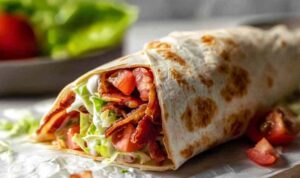 Gourmet BLT wraps cut in half showing layers of bacon, lettuce, tomato, and avocado with secret sauce