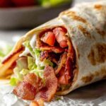 Gourmet BLT wraps cut in half showing layers of bacon, lettuce, tomato, and avocado with secret sauce
