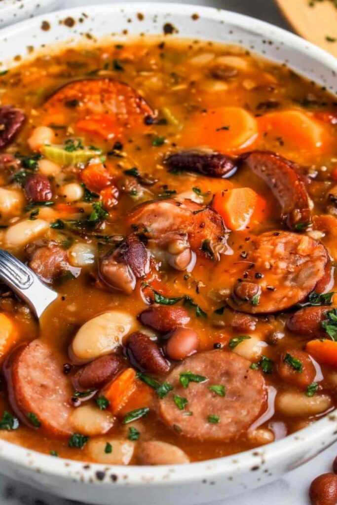 Hearty bean soup with smoked sausage in white bowl with crusty bread