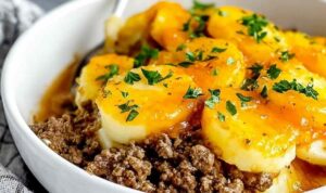 Hobo casserole ground beef in baking dish with melted cheese topping