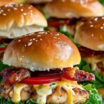 Honey mustard chicken sliders on white plate with shredded lettuce and Swiss cheese