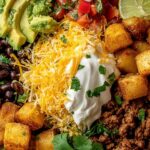 Loaded potato taco bowl with crispy roasted potatoes topped with seasoned ground beef cheese sour cream and fresh vegetables