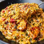 One-pot Cajun chicken Alfredo orzo in skillet with creamy sauce and fresh parsley garnish