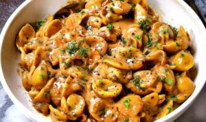 One-pot French onion pasta in a Dutch oven topped with melted gruyere cheese and fresh parsley