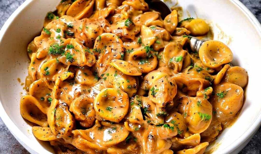 One-pot French onion pasta in a Dutch oven topped with melted gruyere cheese and fresh parsley